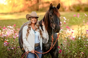 Girl standing in a vibrant wildflower field with her horse